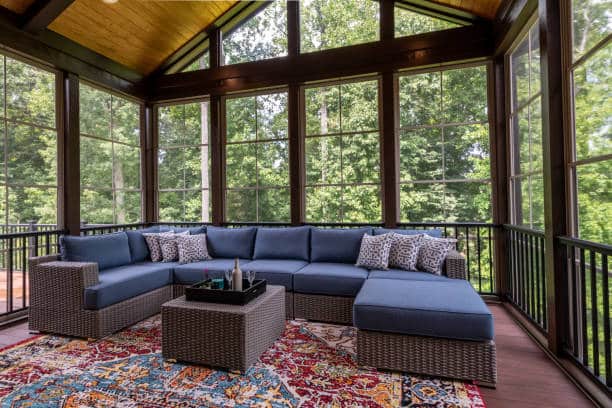 New modern screened porch with patio furniture, summertime woods in the background. New home addition concept.